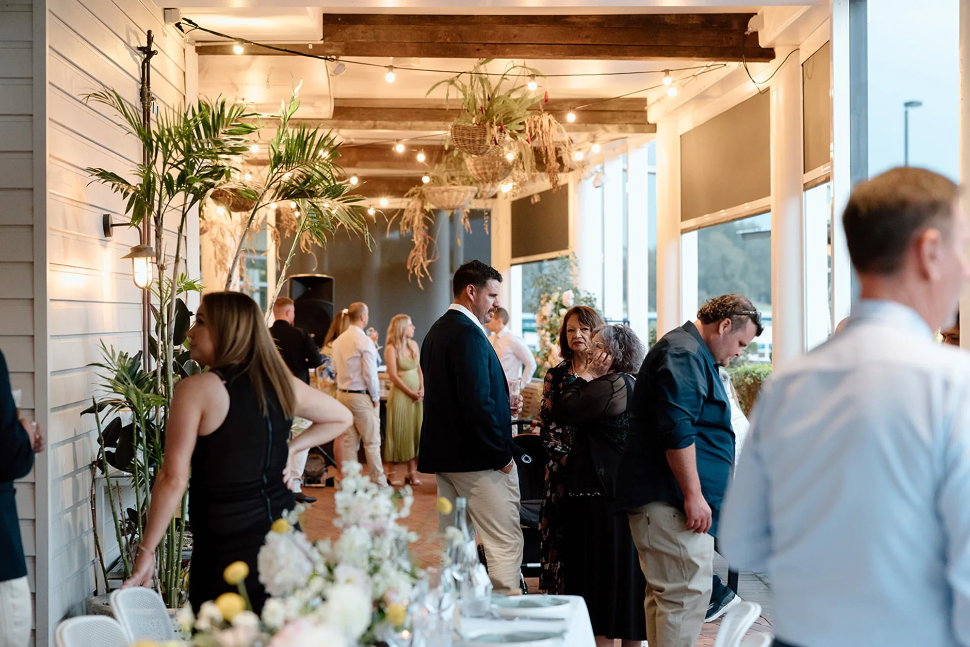 Guests at a function under the veranda, with festoon lights above the tables